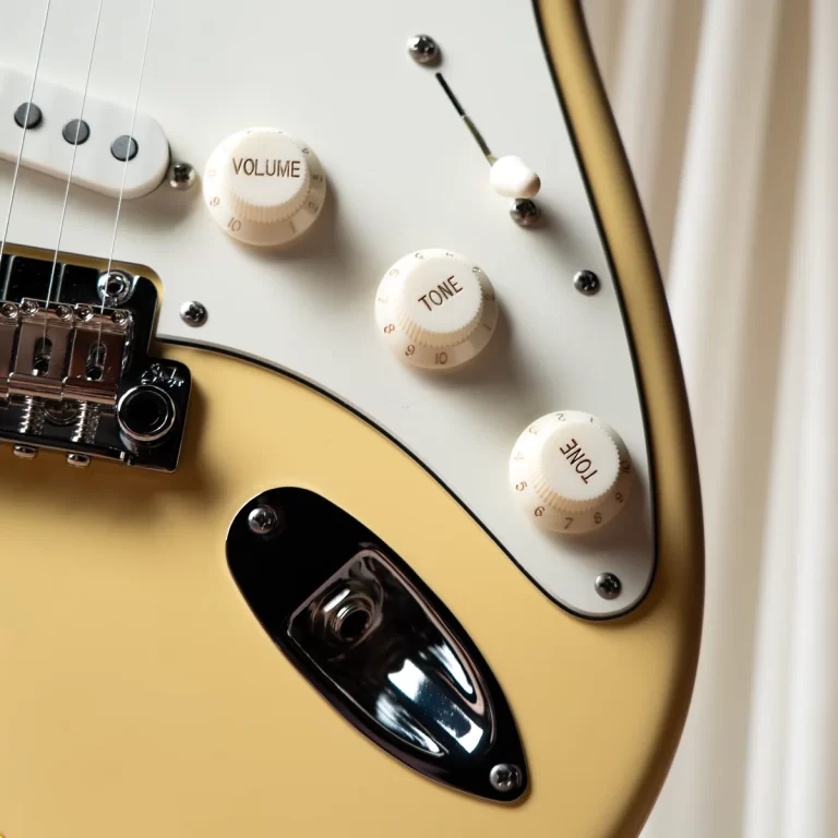 Close-up of a cream-colored electric guitar body with white volume and tone knobs and chrome hardware ขายราคาพิเศษ