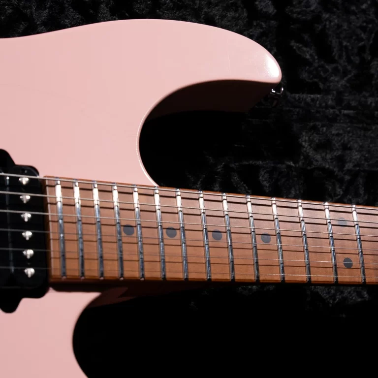 Close-up of a pink electric guitar showing the maple fretboard, frets, and pickup against a dark background ขายราคาพิเศษ