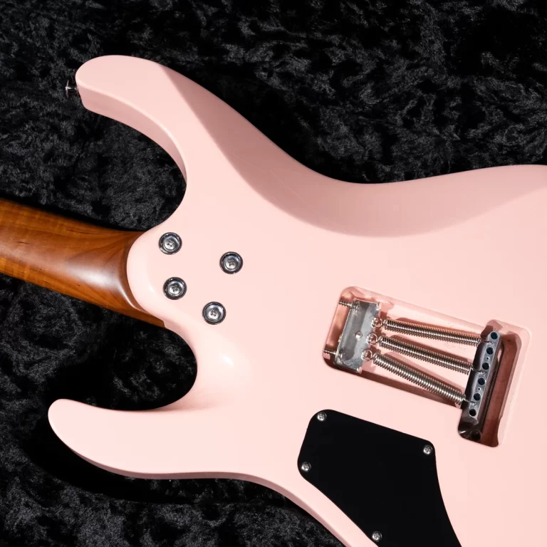 Back view of a pastel pink electric guitar body with tremolo springs and a black rear plate on a black textured surface. ขายราคาพิเศษ