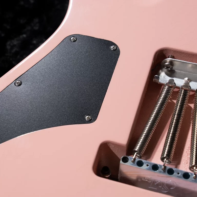 Close-up of a pink electric guitar body showing the tremolo springs and bridge saddles. ขายราคาพิเศษ