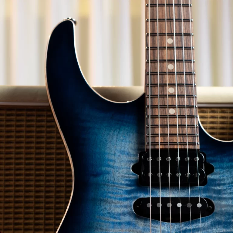 Close-up of a blue electric guitar body and wooden neck with frets and strings visible. ขายราคาพิเศษ