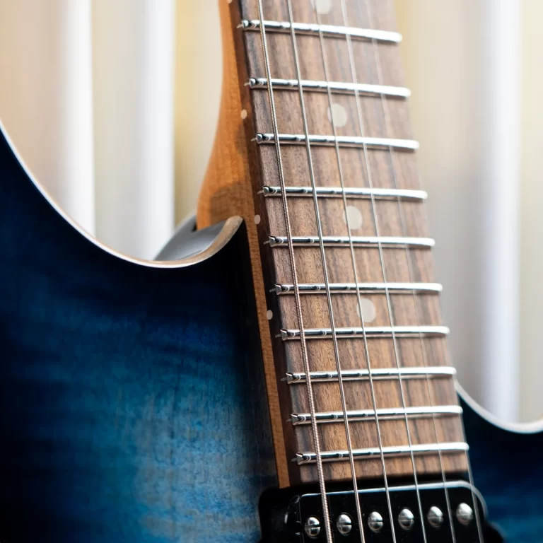 Close-up of an electric guitar neck showing frets and strings on a blue gradient body ขายราคาพิเศษ