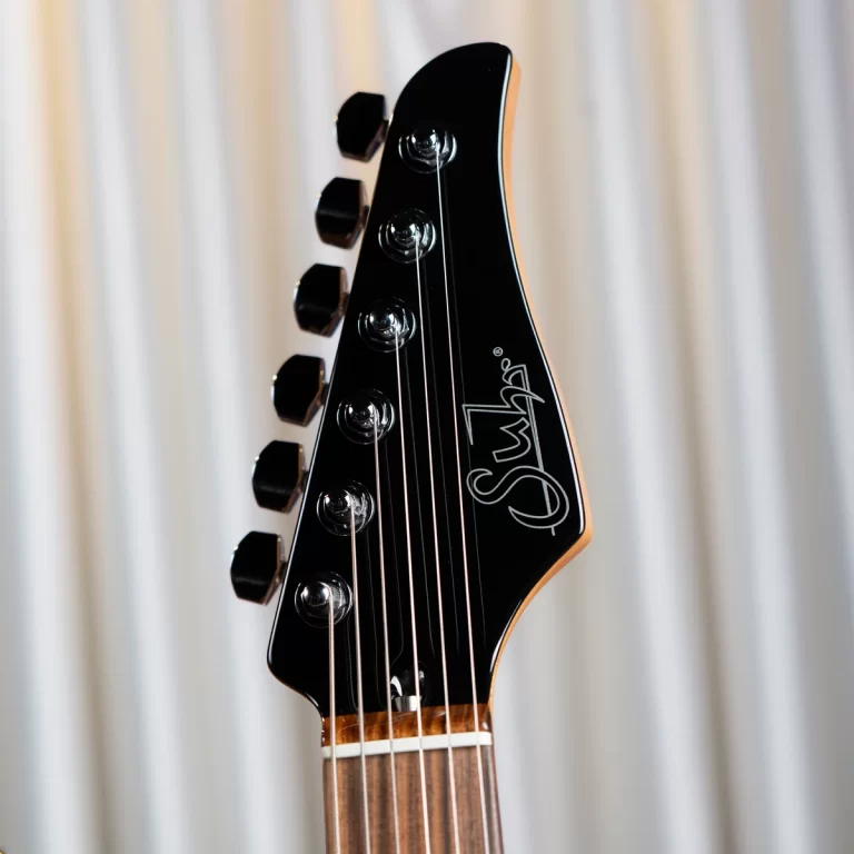 Close-up of a black electric guitar headstock with six chrome tuning pegs and white logo on the right side of the headstock. ขายราคาพิเศษ