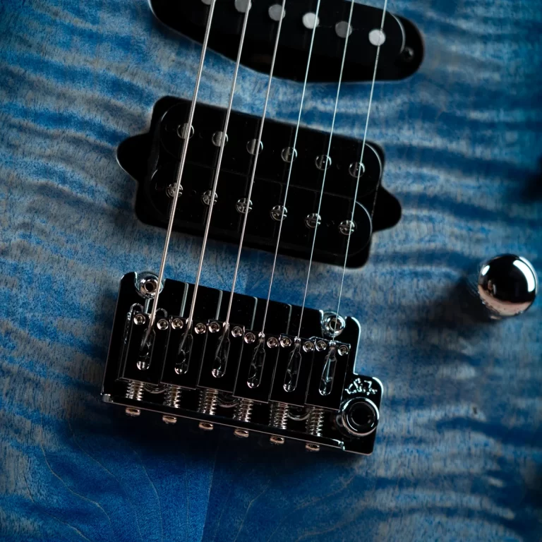 Close-up of a blue electric guitar showing the bridge, pickups, and six strings. ขายราคาพิเศษ