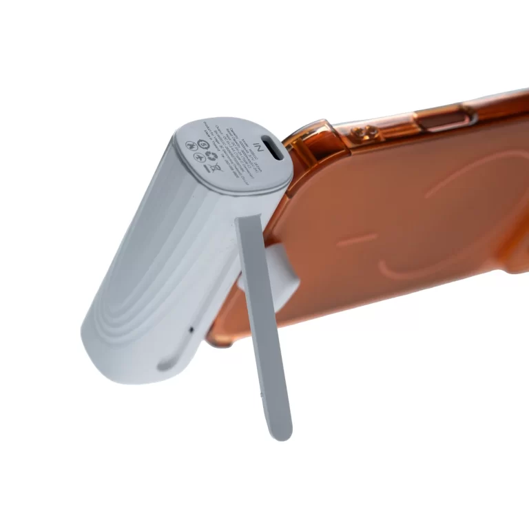 Close-up of a white ribbed attachment with a gray lever and a slim metal pin, connected to an orange translucent smartphone case. ขายราคาพิเศษ
