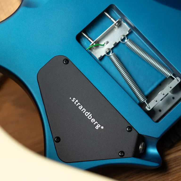 Blue Strandberg electric guitar body with back cavity cover removed, showing two springs and metal tremolo block; green ground wire visible. ขายราคาพิเศษ