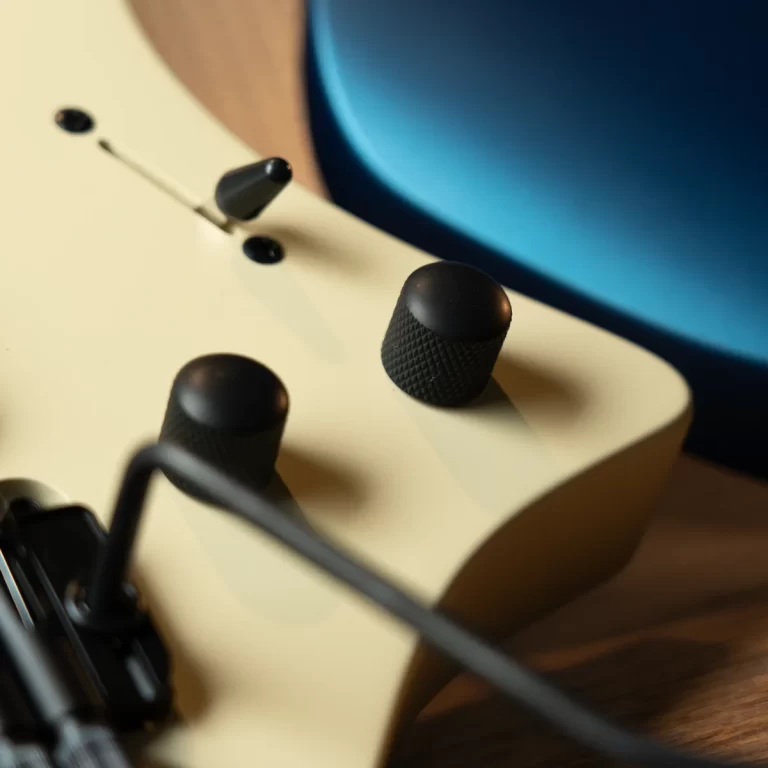 Close-up of a cream-colored electric guitar body with black control knobs and a toggle switch. ขายราคาพิเศษ
