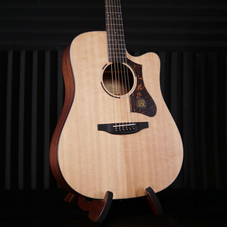 Acoustic guitar with a light natural finish on a stand against a dark background. ขายราคาพิเศษ