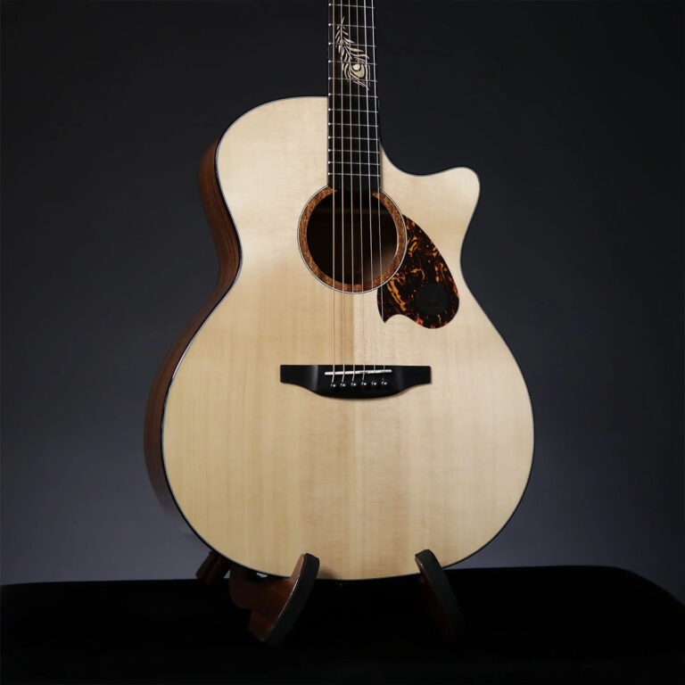 Acoustic guitar with a single cutaway, light spruce top and tortoiseshell pickguard, resting on a stand against a dark backdrop. ขายราคาพิเศษ